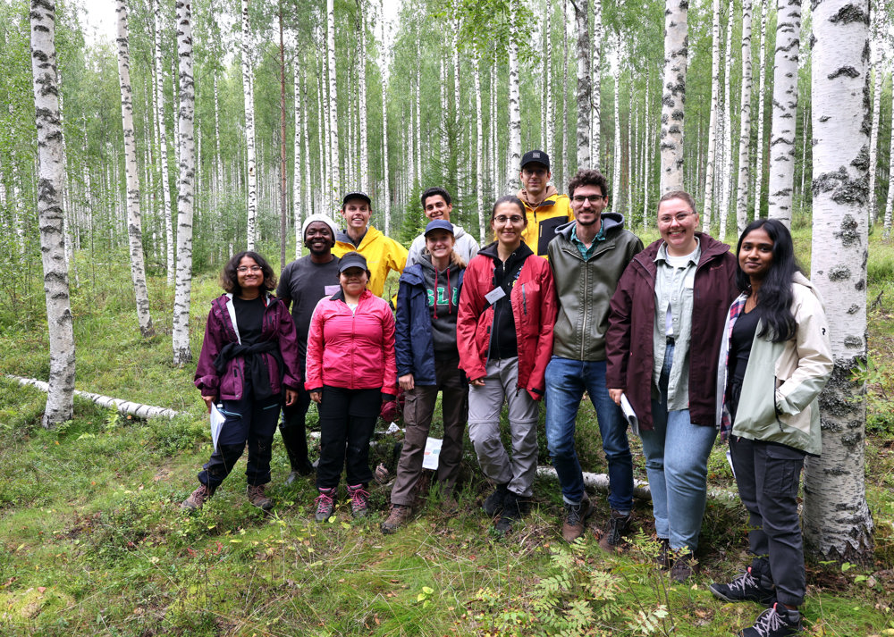 Young people standing in birch forest. Photo.