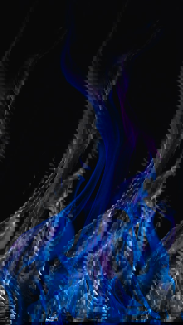 Blå lågor från eld mot mörk bakgrund. Foto.